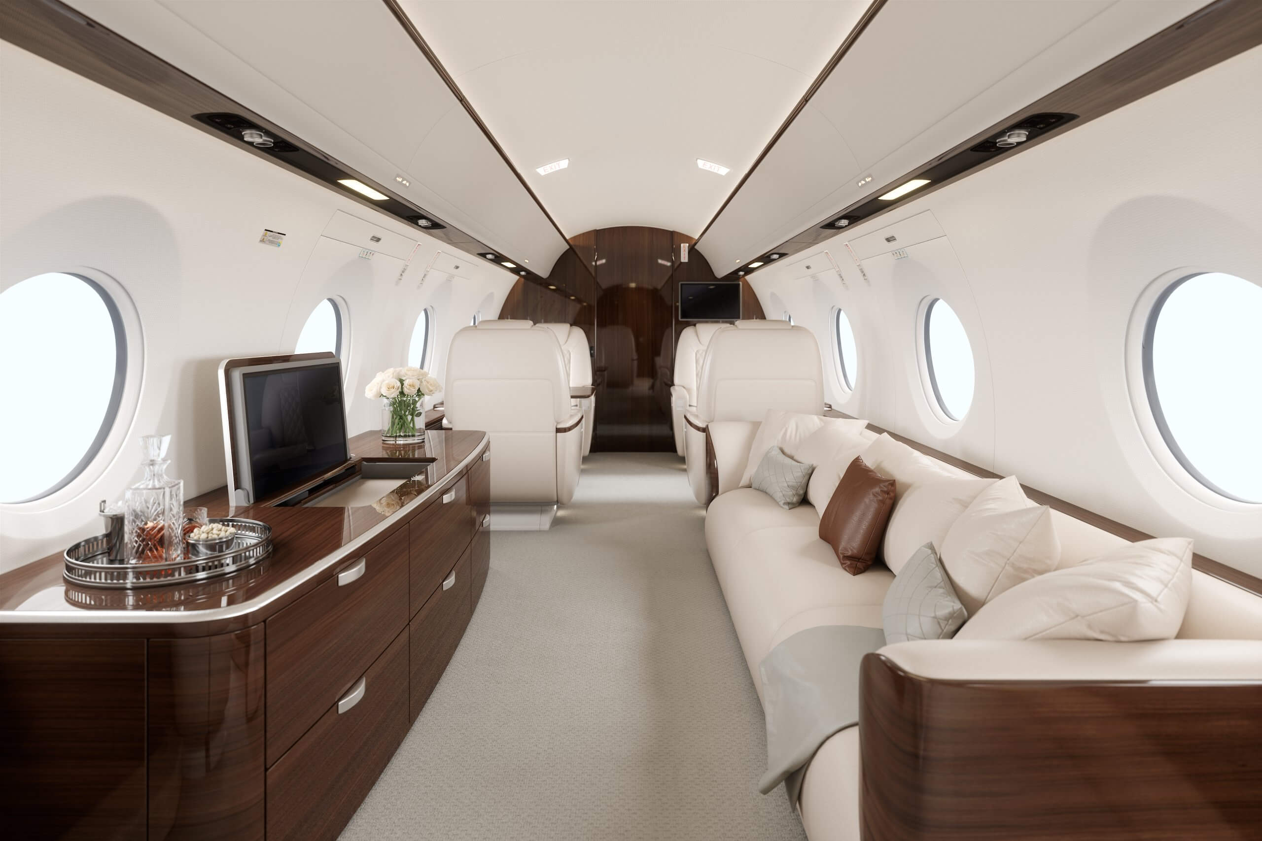 The empty cabin of a large-cabin business jet: facing seats, a divan, and open window shades.